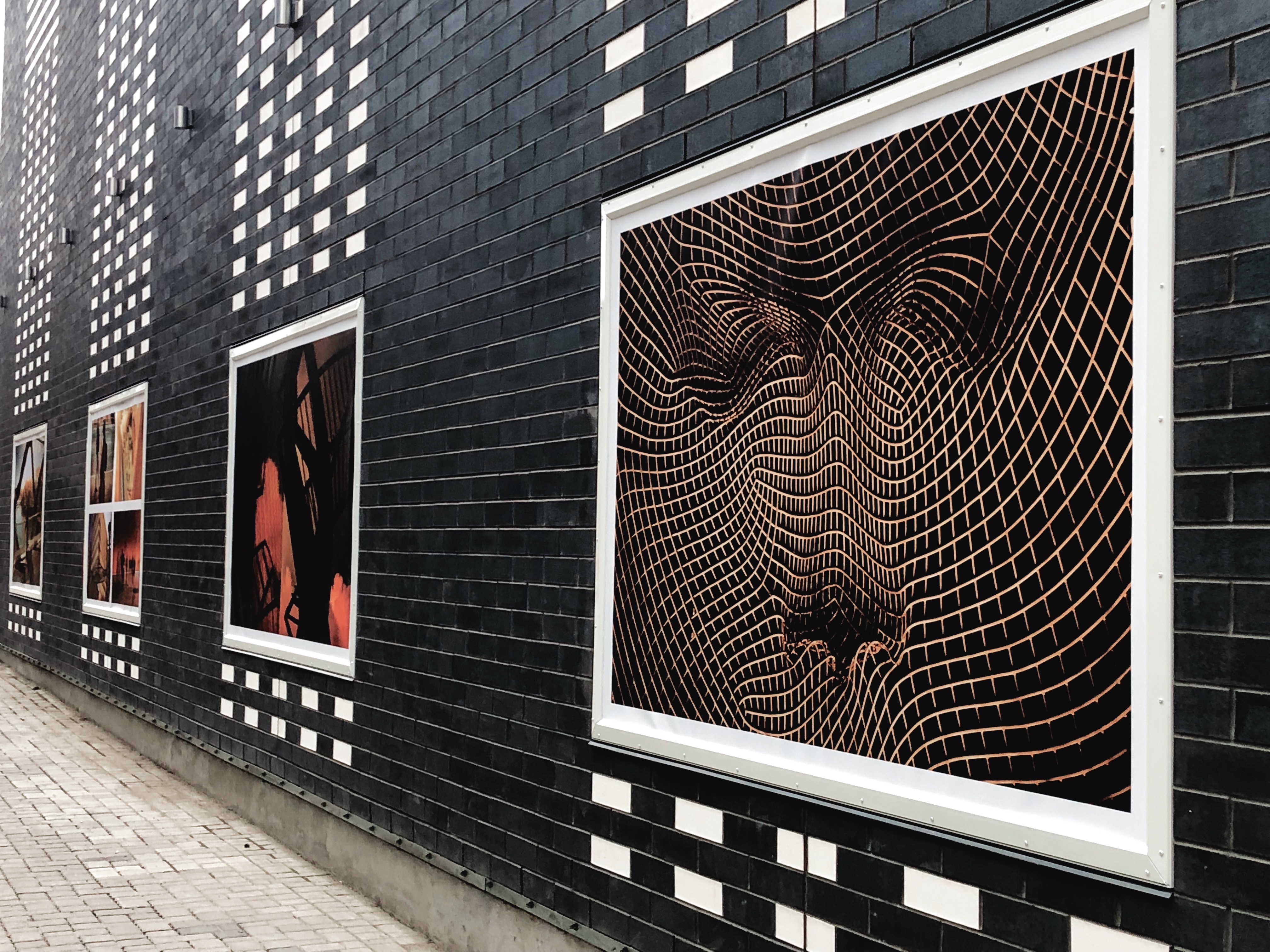 Large Calgary street photographs installed across the black brick exterior of Alt Hotel Calgary.