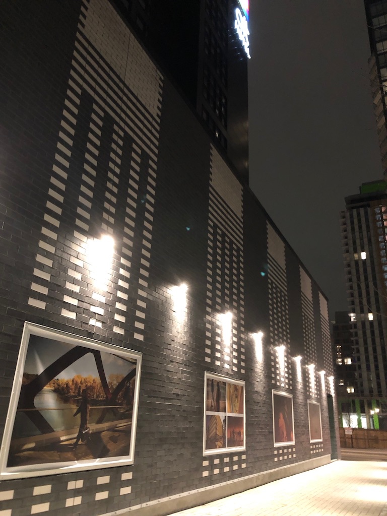 The exterior photographs illuminated at night along the black brick wall of Alt Hotel Calgary.