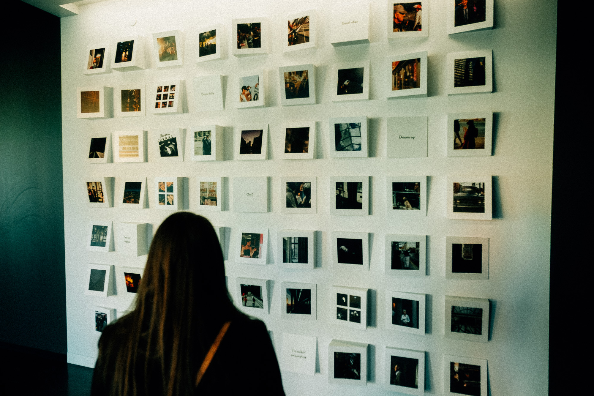 A visitor looking closely at the wall-sized mosaic of Calgary street photographs in Alt Hotel Calgary.