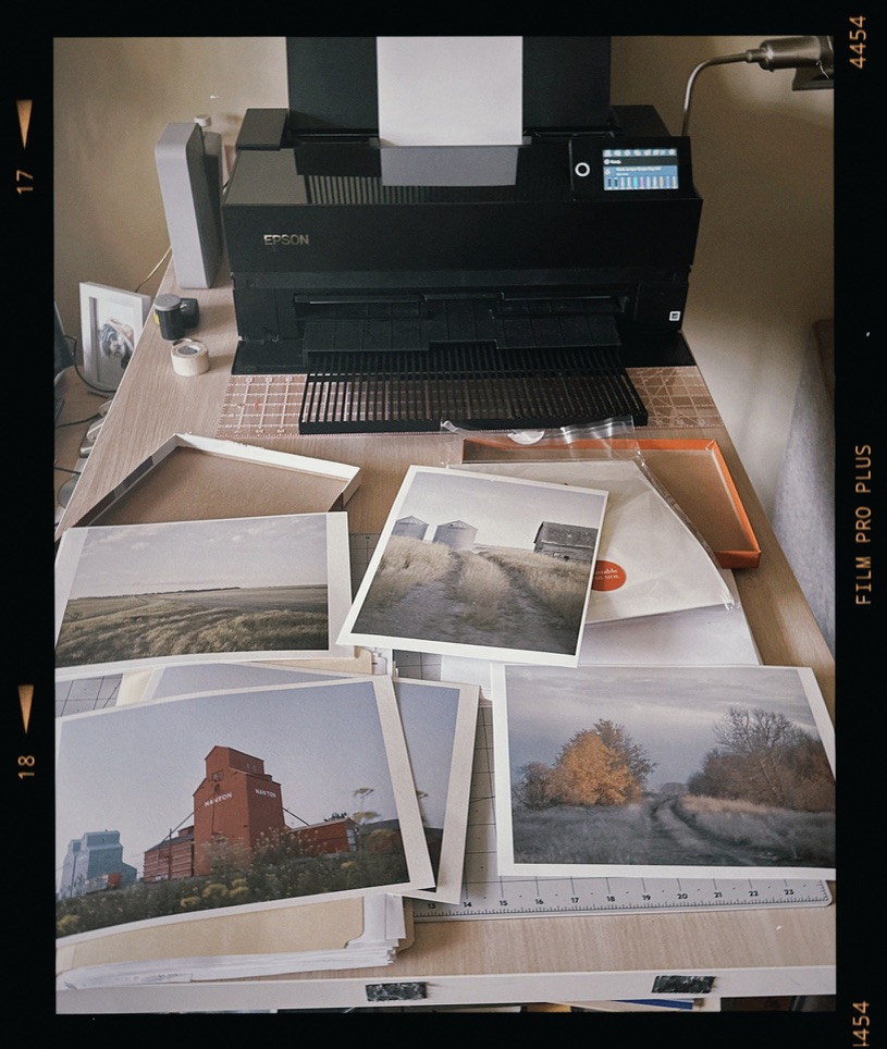 A studio worktable covered with photographic prints beneath the printer.